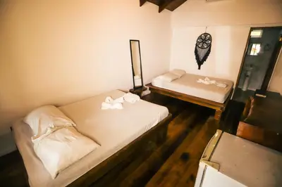 a small room with two beds and a mirror at Cabinas Playa Surf Hostel in Santa Teresa Beach