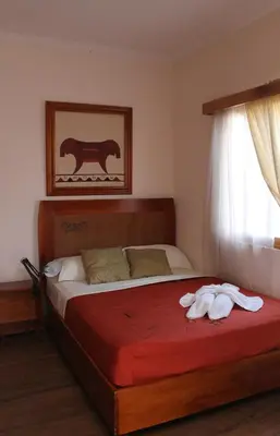 a bedroom with a large bed with a red blanket at Hotel Luz de Luna in San José