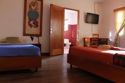 a bedroom with two beds and a television and a door at Hotel Luz de Luna in San José