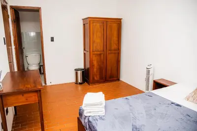 a bedroom with a bed and a desk and a cabinet at Hotel Luz de Luna in San José