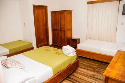 a bedroom with two beds and a wooden table at Hotel Luz de Luna in San José
