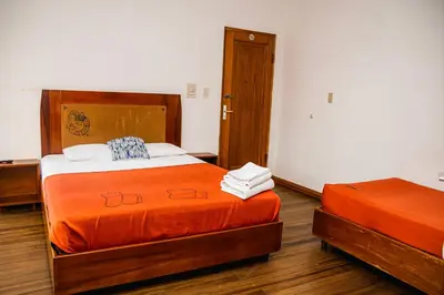 a bedroom with two beds with orange sheets at Hotel Luz de Luna in San José