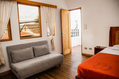 a bedroom with a bed and a couch and a window at Hotel Luz de Luna in San José