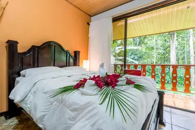 a bedroom with a bed with a flower arrangement on it at Ara Ambigua Lodge in Sarapiquí