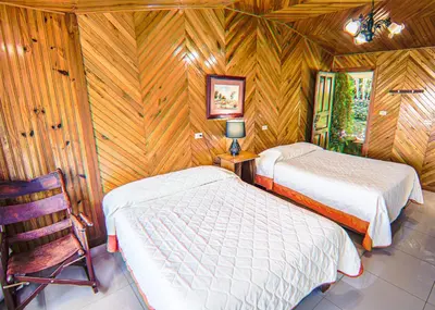 a bedroom with two beds and a chair in it at Hotel Don Taco in Monteverde Costa Rica