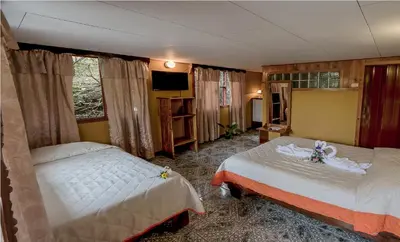 a hotel room with two beds and a television at Hotel Don Taco in Monteverde Costa Rica