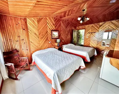 a bedroom with two beds and a chair in it at Hotel Don Taco in Monteverde Costa Rica