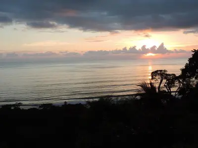 a sunset over the ocean with the sun setting at Ranchos Remo Lodge in Uvita