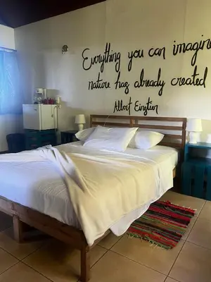 a bedroom with a bed with a sign on the wall at Ranchos Remo Lodge in Uvita