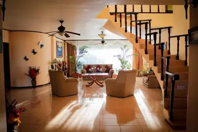 a living room with a staircase with chairs and a table at Villa Alta Bed&Breakfast in Barranca