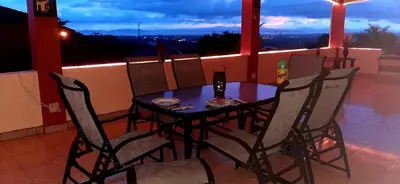 a dining table and chairs on a balcony at night at Villa Alta Bed&Breakfast in Barranca