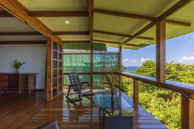 a room with a balcony with a table and a chair at Punta Marenco Lodge in Drake