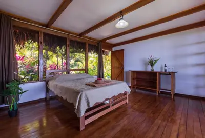 a bedroom with a bed and a table and windows at Punta Marenco Lodge in Drake