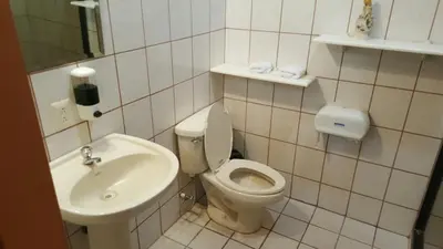 a small bathroom with a toilet and a sink at Hotel La Arena in Liberia