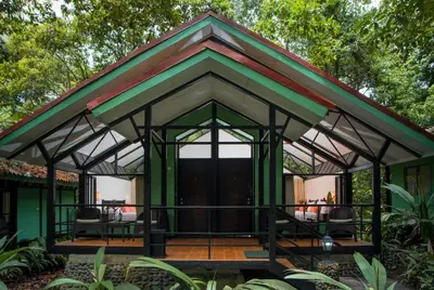 a green house with a gambrel roof at Tapirus Lodge and Reserve in Carrillo