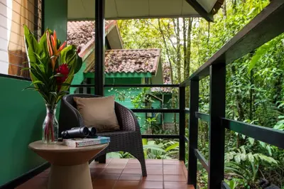 a balcony with a chair and a table with a vase of flowers at Tapirus Lodge and Reserve in Carrillo