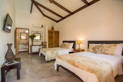 a bedroom with two beds and a mirror at Conchal Hotel in Brasilito