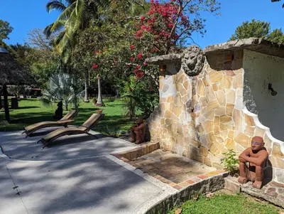 a statue of a lion next to a stone wall at spirit of jungle lodge in Sámara
