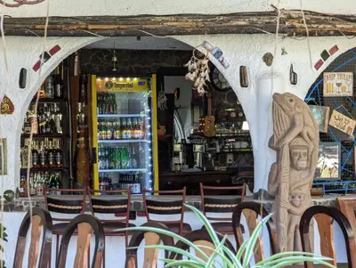 a restaurant with tables and chairs in front of a bar at spirit of jungle lodge in Sámara