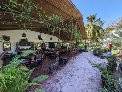 an outdoor restaurant with tables and chairs and plants at spirit of jungle lodge in Sámara