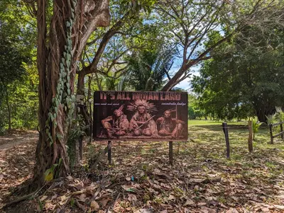 a sign in a park next to a tree at spirit of jungle lodge in Sámara