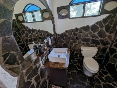 a bathroom with a toilet and a sink and windows at spirit of jungle lodge in Sámara