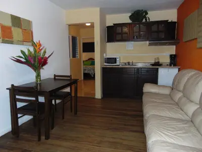 a living room with a couch and a table and a kitchen at Casa Lima B&B in San José