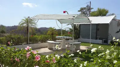 a picnic table under an umbrella in a garden at Barracuda apartments in Sámara
