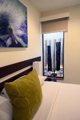 a bedroom with a bed with a green pillow on it at Isla Verde Hotel in San José