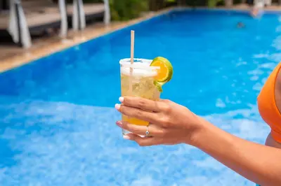 a woman holding a drink in front of a pool at Leyenda Boutique Hotel & Spa in Sámara
