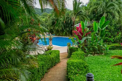 a swimming pool in a garden with trees and plants at Leyenda Boutique Hotel & Spa in Sámara