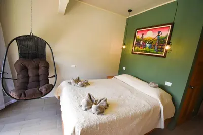 a bedroom with a bed and a swing and a chair at Cabinas Eddy B&B in Monteverde Costa Rica