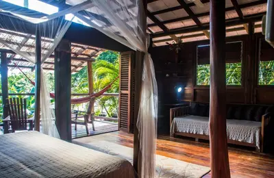 a bedroom with a bed and a view of the forest at Funky Monkey Lodge in Santa Teresa Beach