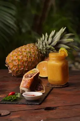 a table with bread and a bottle of mustard and a pineapple at Funky Monkey Lodge in Santa Teresa Beach