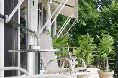 a porch with chairs and a table and plants at Funky Monkey Lodge in Santa Teresa Beach