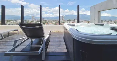a chair sitting next to a hot tub on a roof at BEE Suites San José - Escalante in San José