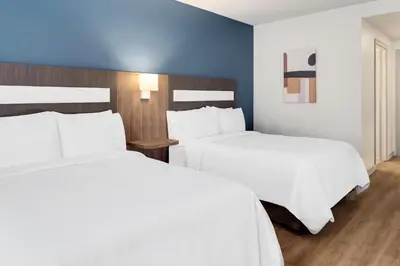 two beds in a hotel room with white sheets at Holiday Inn Express San Jose Forum by IHG in San José