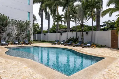 a swimming pool with chairs and palm trees at Holiday Inn Express San Jose Forum by IHG in San José