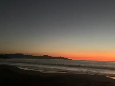 a sunset on the beach with mountains in the background at Casa vacacional Tamarindo beach in Guatemala