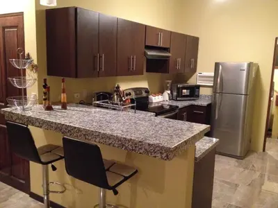 a kitchen with a granite counter top and a refrigerator at Casa vacacional Tamarindo beach in Guatemala