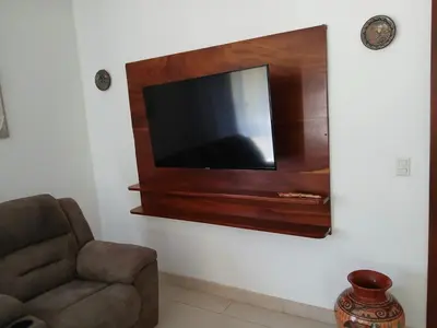 a living room with a chair and a television on a wall at Peaceful and beautiful Casa Almita Bonita in Sámara