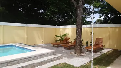 a swimming pool with two chairs and a tree at Peaceful and beautiful Casa Almita Bonita in Sámara