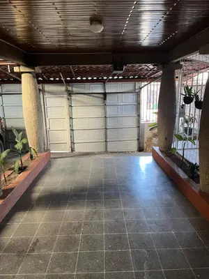 a garage with two white garage doors and some plants at El mochilero in Cartago