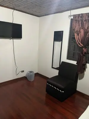 a living room with a chair and a mirror at El mochilero in Cartago