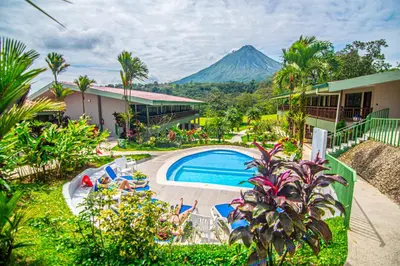 a resort with a pool and a mountain in the background at Hotel Lavas Tacotal in Fortuna