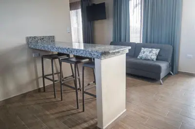 a kitchen with a bar with stools and a couch at Hotel Lavas Tacotal in Fortuna