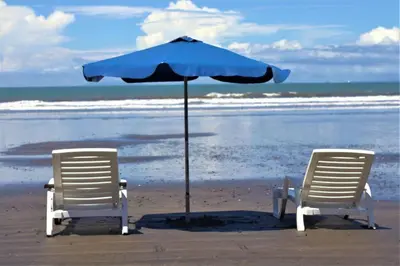two chairs and an umbrella on the beach at Costa Linda 1-19, walking distance from the beach in Jacó