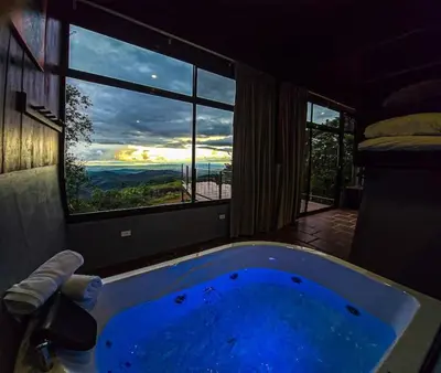 a bath tub in a room with a window at Sunset Vista Lodge,Monteverde,Costa Rica. in Monteverde Costa Rica