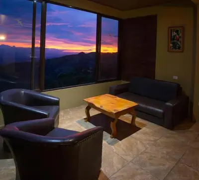 a living room with a couch and a table at Sunset Vista Lodge,Monteverde,Costa Rica. in Monteverde Costa Rica