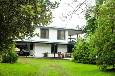 a white house with people sitting in a yard at Casa Kamagu in Fortuna